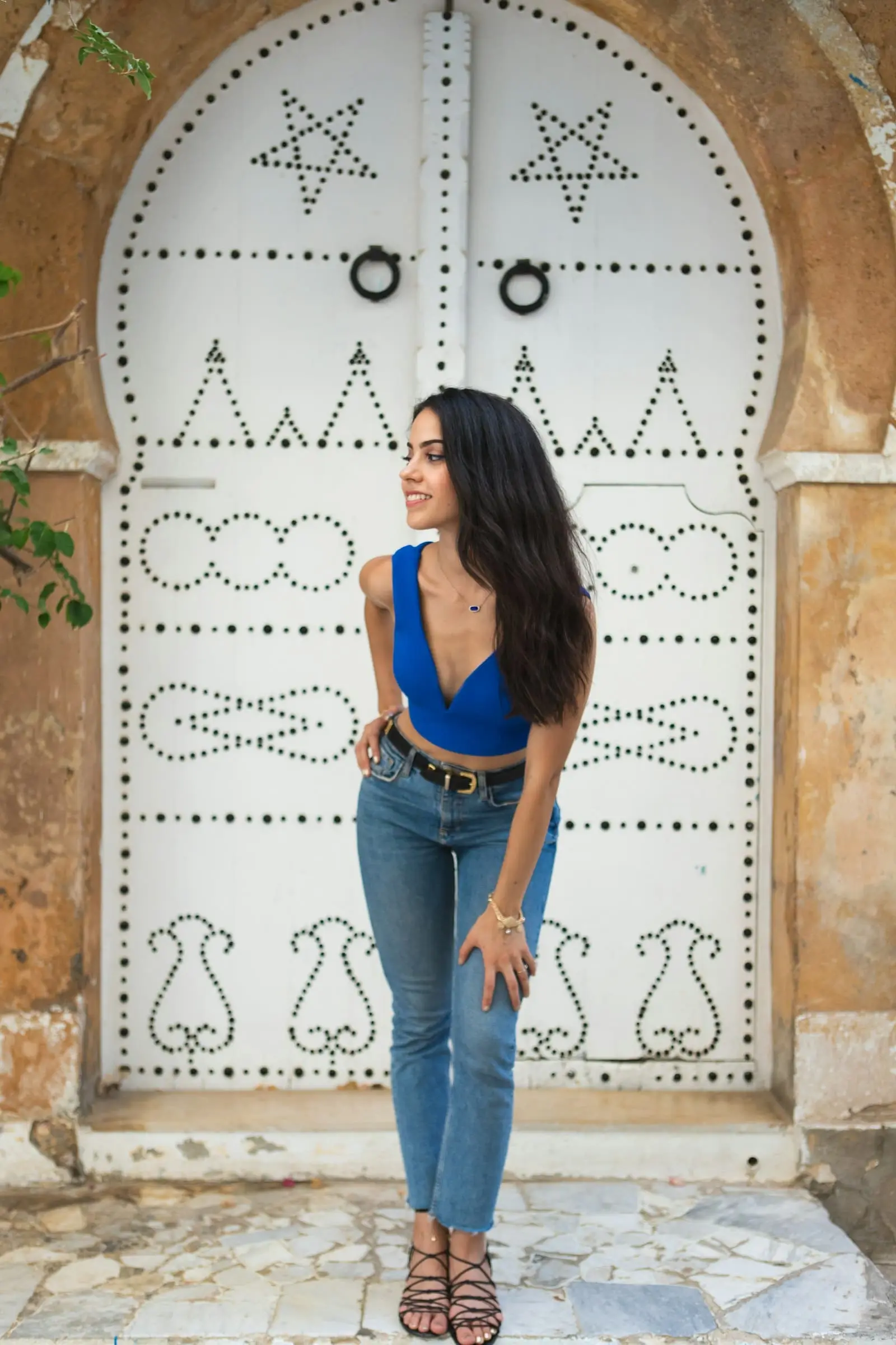 Femme devant une porte tunisienne cloutée